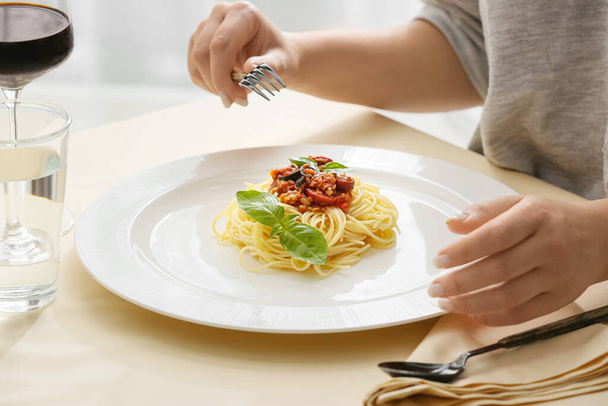 Woman eating tasty Pasta Puttanesca at table in restaurant, closeup - Foto, afbeelding