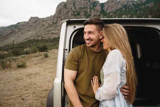 Young happy couple on a road trip sitting in car trunk - Foto, imagen