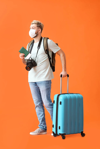 Turista masculino en máscara médica sobre fondo de color - Foto, imagen