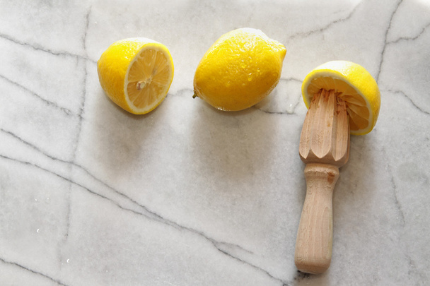 Fresh lemons and citrus reamer on marble - Photo, Image