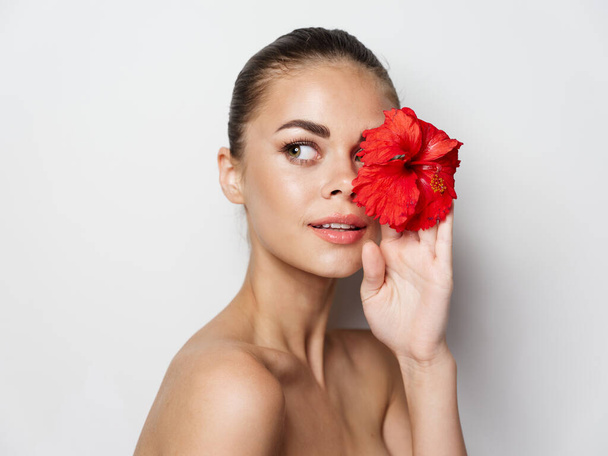beautiful woman on a light background with a flower in her hand cropped view - Foto, Imagem