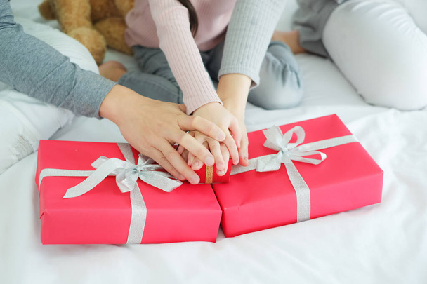 Крупним планом рука азіатської родини батько і мати і дочка з червоною подарунковою коробкою
 - Фото, зображення