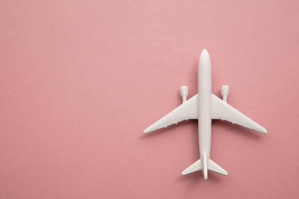 weißes Spielzeugflugzeug auf pastellrosa Hintergrund. Flugreise Hintergrund mit Kopierraum - Foto, Bild