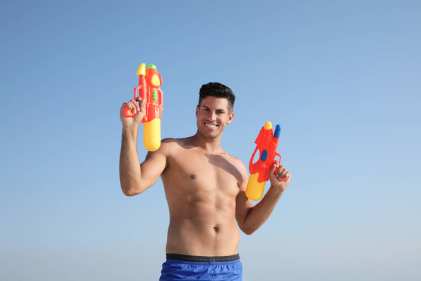 Man with water guns against blue sky - Фото, зображення