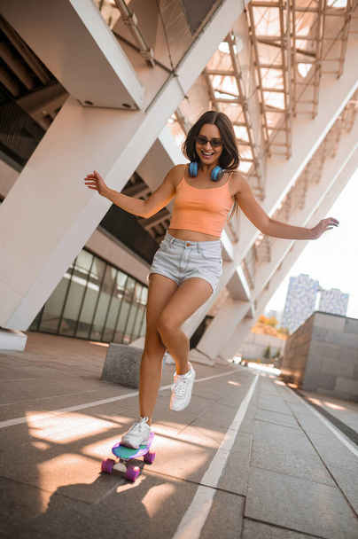 A picture of a cute girl in orange top on the urban background - Foto, imagen