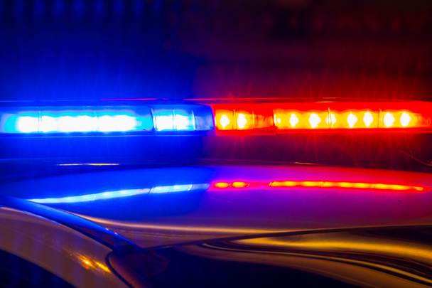 policejní auto s blikajícími světly s červenými a modrými barvami na rozmazaném pozadí městské ulice - Fotografie, Obrázek