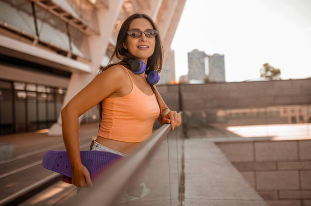 A picture of a cute girl in orange top on the urban background - Φωτογραφία, εικόνα
