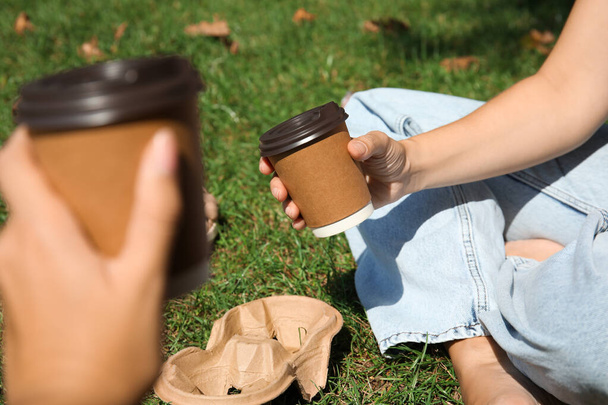 Women holding takeaway cardboard coffee cups with plastic lids outdoors, closeup - Fotó, kép