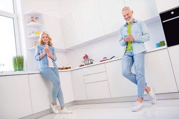 Full size photo of happy smiling married couple browsing in smartphone social media user indoors kitchen room - Фото, изображение