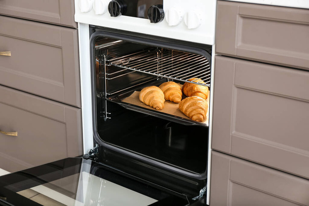 Modern electric oven with croissants in kitchen - Photo, Image