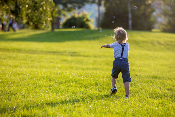 Aranyos óvodás gyerek, aki a parkban játszik naplementekor. - Fotó, kép