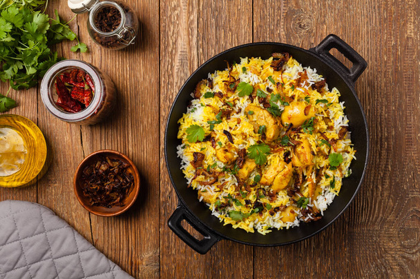 Biryani with chicken. Traditional Indian dish of rice and chicken marinated in spices and yoghurt.Top view. natural wooden background.  - Фото, изображение