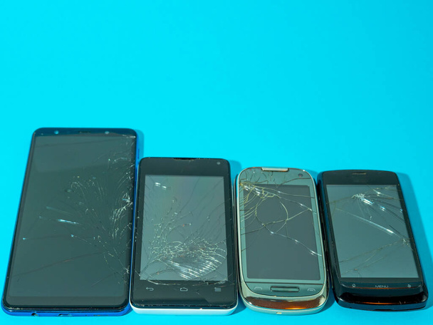 Black rozbił smartfon z zepsutym ekranem i ciała na niebieskim stole w służbie. - Zdjęcie, obraz