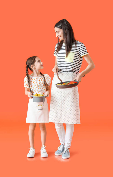Młoda matka i córka ze smacznymi daniami na tle koloru - Zdjęcie, obraz