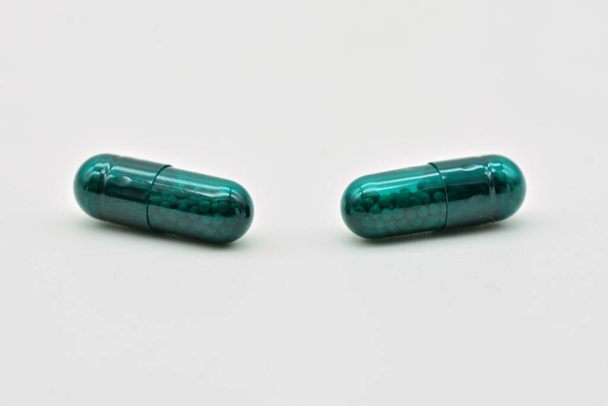 Forma farmacéutica de cápsulas verdes, aisladas sobre fondo blanco - Foto, Imagen