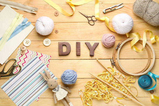 Composition with word DIY and knitting supplies on wooden background - Photo, Image