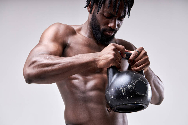 Portrait of strong young african man working out with kettle bell. Isolated white background - Foto, Imagem