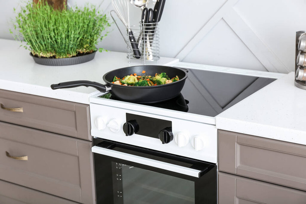 Сковородка с овощами на плите на кухне - Фото, изображение