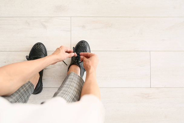 Mujer joven atando cordones de zapatos en casa - Foto, imagen