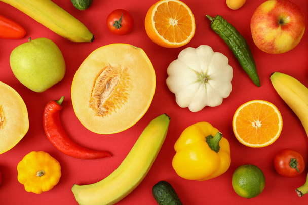 Набор различных овощей и фруктов на красном фоне - Фото, изображение