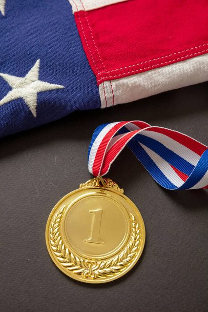 Medal gold for USA. Winner prize award with ribbon and US flag on black background. American athlete trophy in sport for first place champion. - 写真・画像