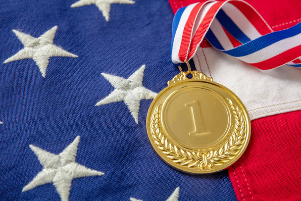 Medal gold for USA. Winner prize award with ribbon on US flag background. American athlete trophy in sport for first place champion. Number one and laurel wreath, - 写真・画像