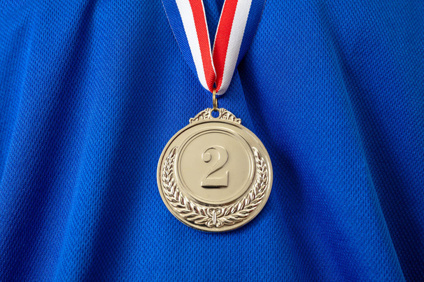 Mitali hopeaa. Voittaja palkinnon roikkuu punainen sininen väri nauha urheilija rinnassa. Trophy in sport toiseksi mestari sininen väri paita tausta - Valokuva, kuva