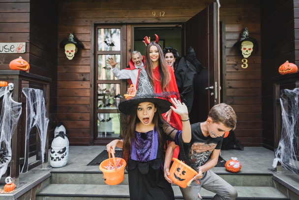 scared kids in halloween costumes screaming while running out house from spooky neighbors - Photo, Image