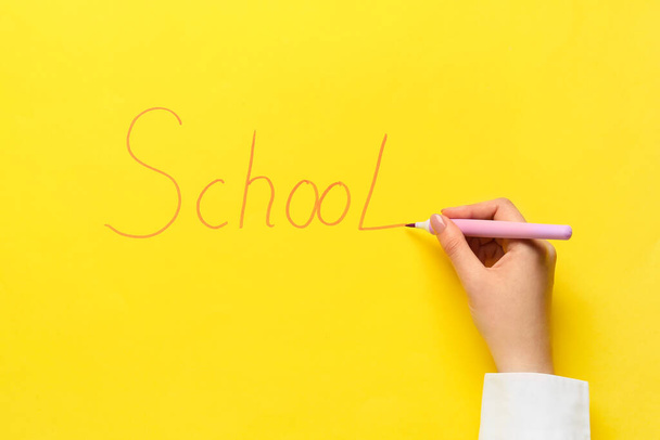Nő írás szó SCHOOL filctollal színes háttér - Fotó, kép