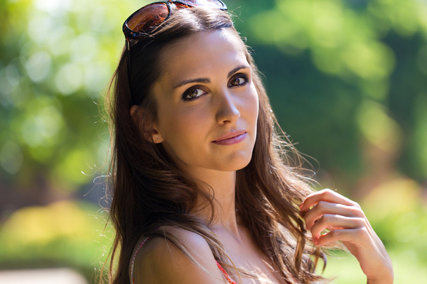 Beautiful woman with dark hair and brown eyes posing at garden. - Foto, afbeelding