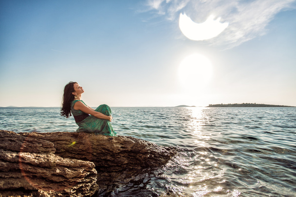 сидячи на скелі, на березі Адріатичного моря в зелений плаття дівчина - Фото, зображення