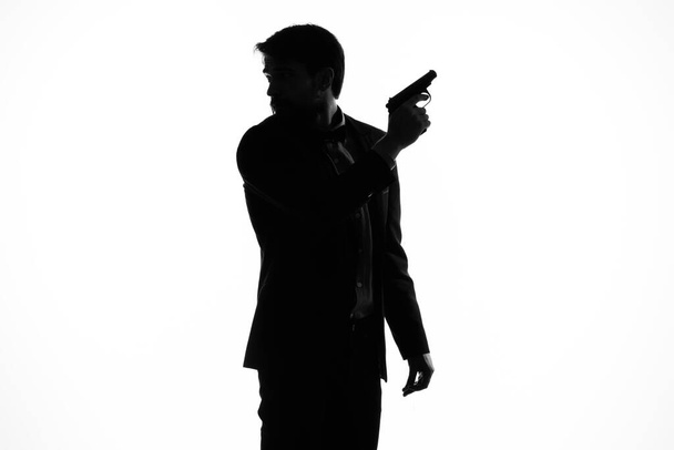 L'homme en costume pistolet dans les mains de l'émotion silhouette fond clair - Photo, image