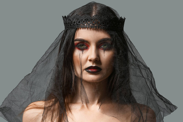 Beautiful woman dressed as witch for Halloween on grey background - Valokuva, kuva