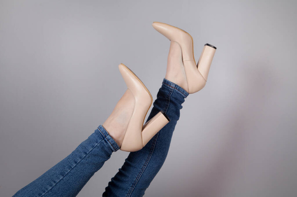 Ноги жінки в стильному високому взутті, на сірому фоні
. - Фото, зображення