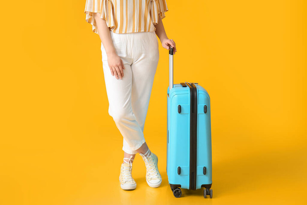 Female tourist with luggage on color background - Φωτογραφία, εικόνα