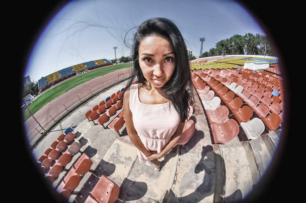 Retrato de modelo asiático posando en el estadio de pie sobre los asientos brillantes
 - Foto, Imagen