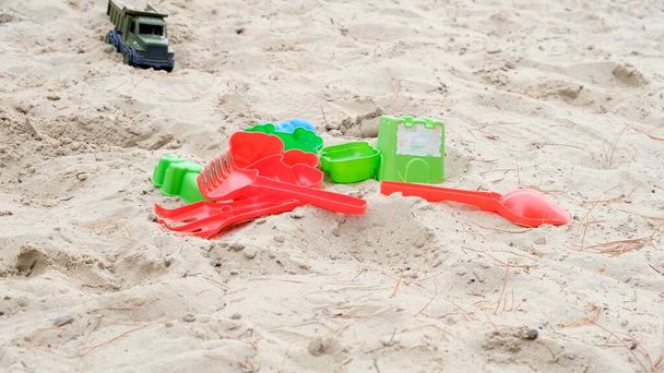Plastikowe zabawki dla dzieci leżące na białym piasku. Koncepcja gry letniej i zajęcia dla dzieci - Zdjęcie, obraz