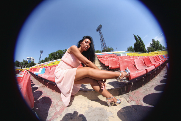 Retrato de modelo asiático posando en el estadio de pie sobre los asientos brillantes
 - Foto, imagen