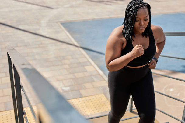 obese young african woman foing fitness exercises on stairs outdoors. weight loss - Foto, Imagem