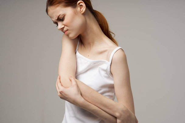 mujer en camiseta blanca reumatismo codo dolor problemas de salud fondo claro - Foto, imagen