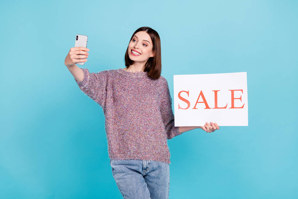 Foto van vrolijke blogger dame houden telefoon verkoop plakkaat nemen selfie wear pullover geïsoleerde blauwe kleur achtergrond - Foto, afbeelding