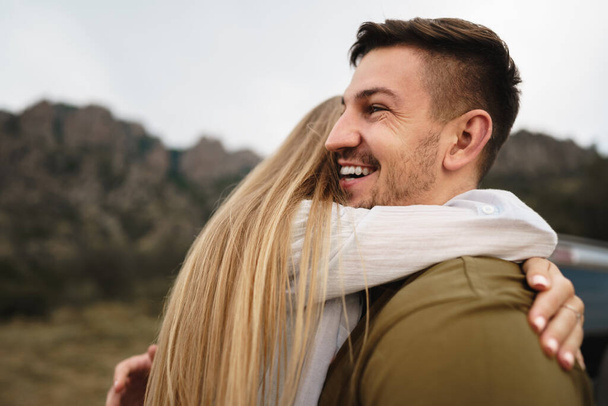 Happy loving couple hiking and hugging in mountains - Фото, изображение
