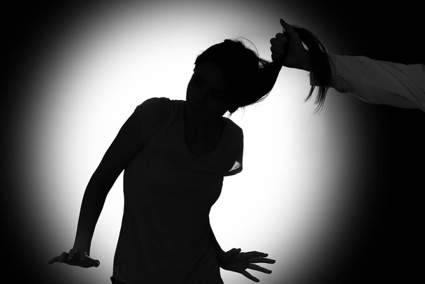 Silhouette of woman mistreated by man on dark background - Photo, image