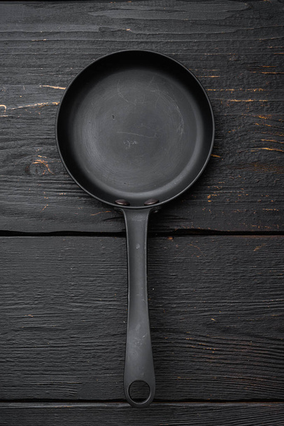 Σκεύος τηγανιτού χυτοσιδήρου με χώρο αντιγραφής κειμένου ή φαγητού με χώρο αντιγραφής κειμένου ή φαγητού, επίπεδη επιφάνεια προβολής, σε μαύρο ξύλινο τραπέζι - Φωτογραφία, εικόνα