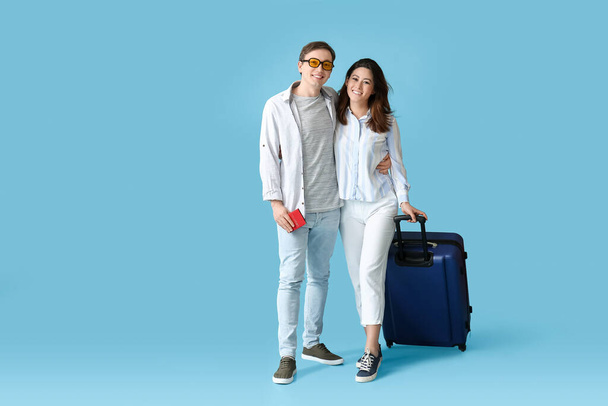 色の背景に荷物を持つ観光客のカップル - 写真・画像