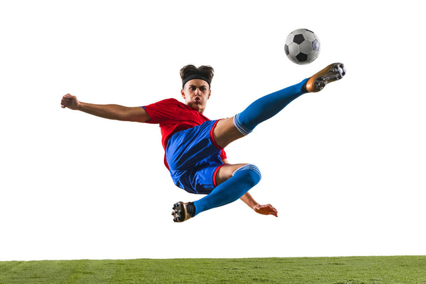 Portrait horizontal complet du jeune homme, footballeur s'entraînant isolé sur fond blanc. Dans un saut - Photo, image