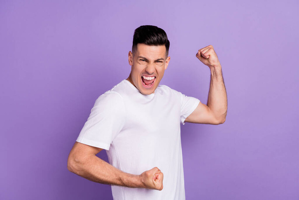 Photo of cheerful positive young happy man winner raise fists celebrate hooray isolated on violet color background - Zdjęcie, obraz