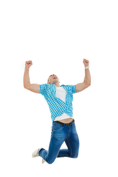 man in blue shirt and jeans jumping in the air with his hands ra - Foto, afbeelding