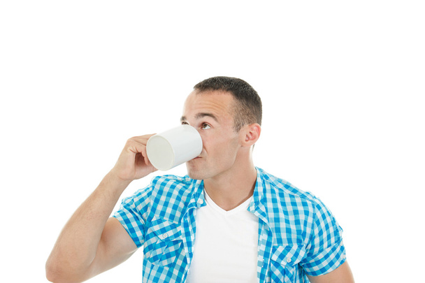 Young muscular guy drinking coffee or tea enjoying it - Zdjęcie, obraz