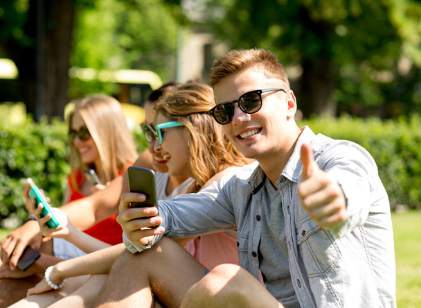 smiling man with smartphone showing thumbs up - Photo, Image